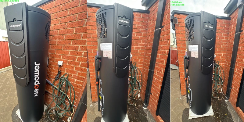 New Neopower heat pump hot water system installed against a red brick wall outdoors, replacing the old Proflo unit